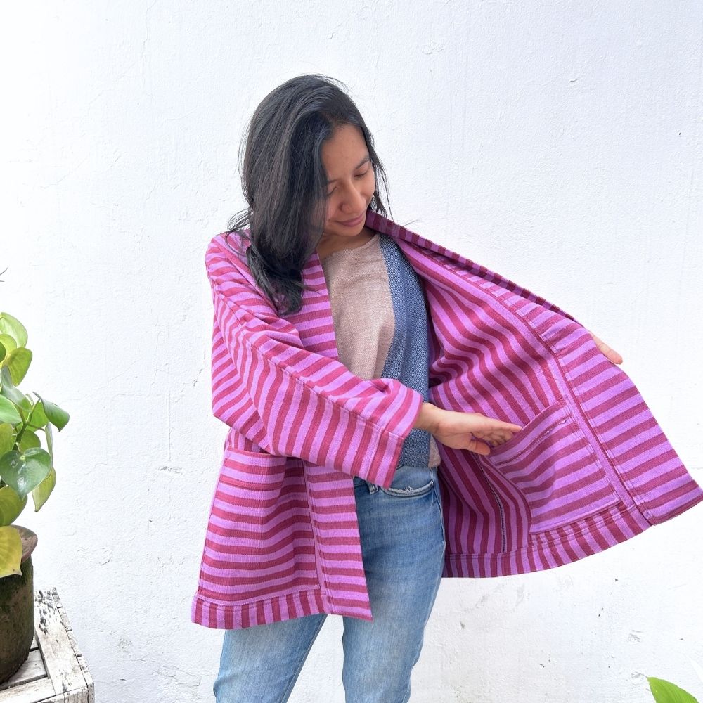 Woman wearing a pink and purple striped coat against a white background