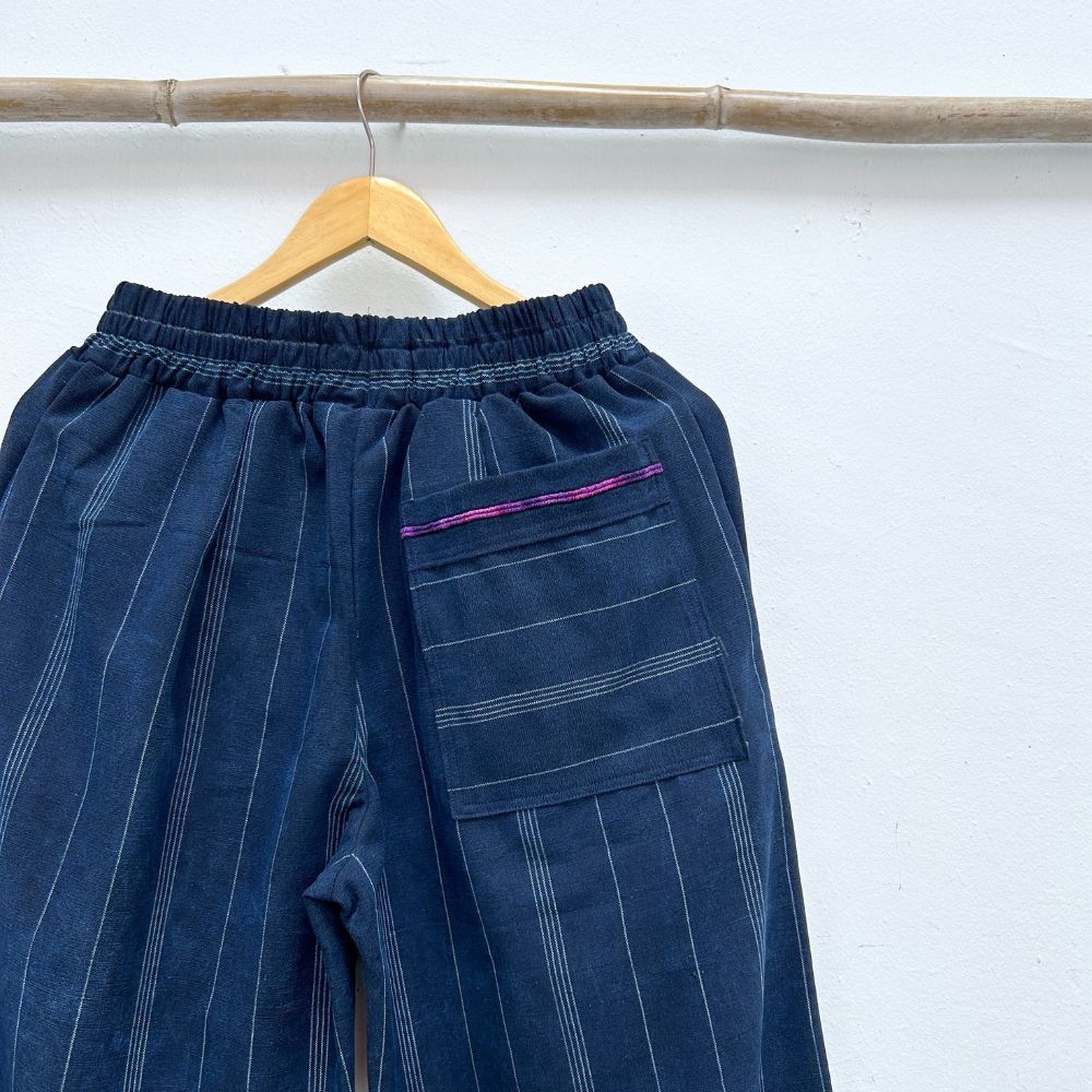 Blue pinstripe pants on a wooden hanger against a white background