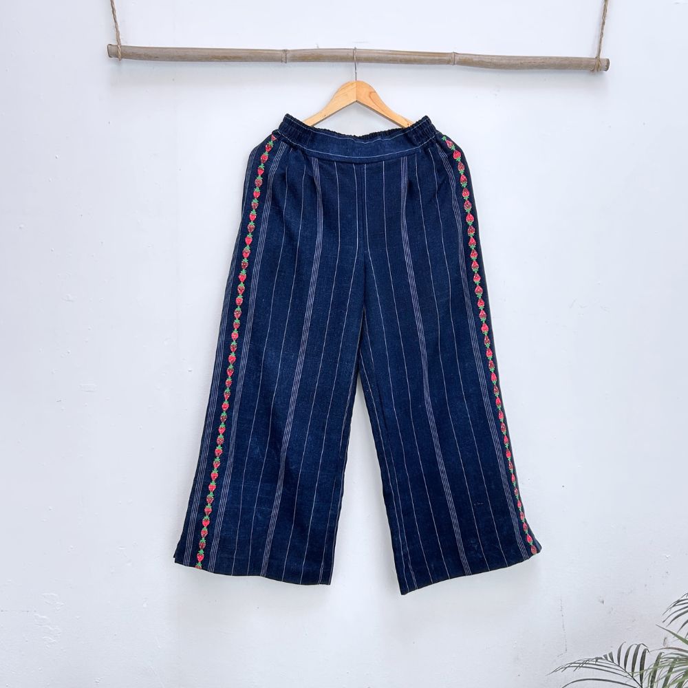 Navy blue pinstripe trousers with strawberries randa embroidery  on a hanger against a white background