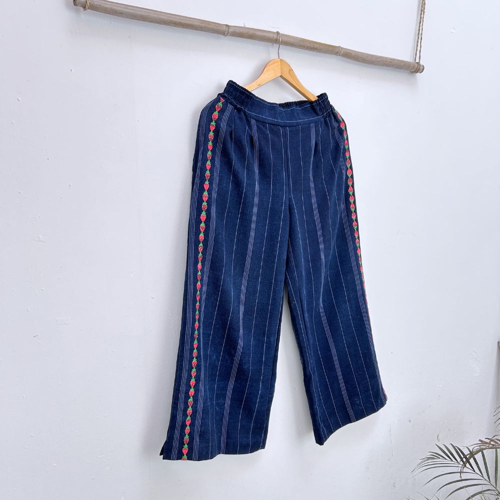 Navy blue pinstripe trousers with strawberries randa embroidery  on a hanger against a white background