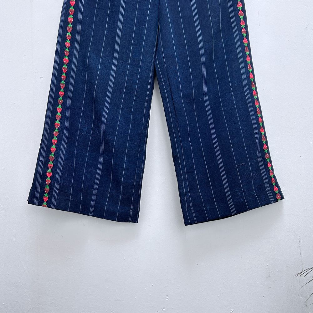 Navy blue pinstripe trousers with strawberries randa embroidery  on a hanger against a white background