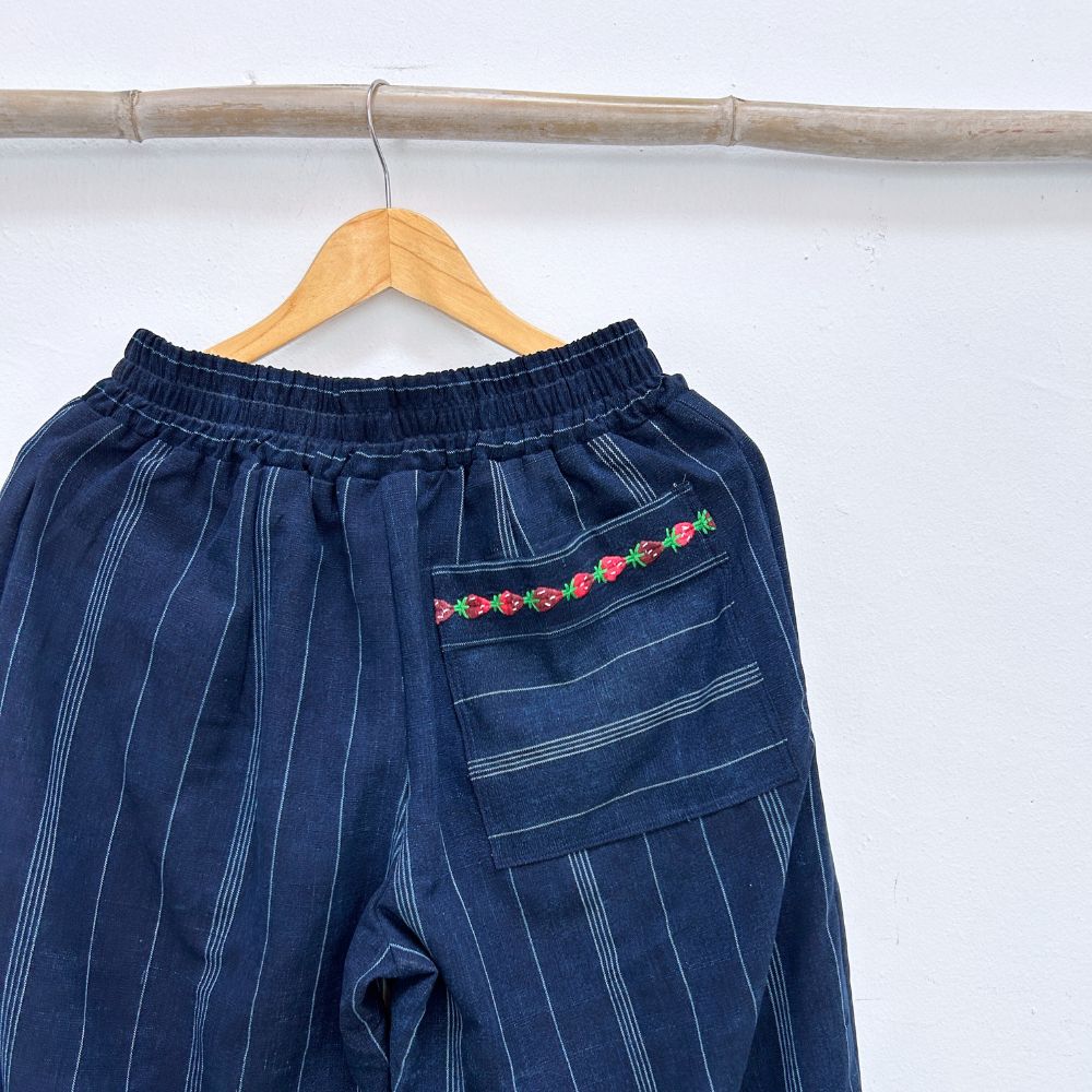 Navy blue pinstripe trousers with strawberries randa embroidery  back pocket  on a hanger against a white background