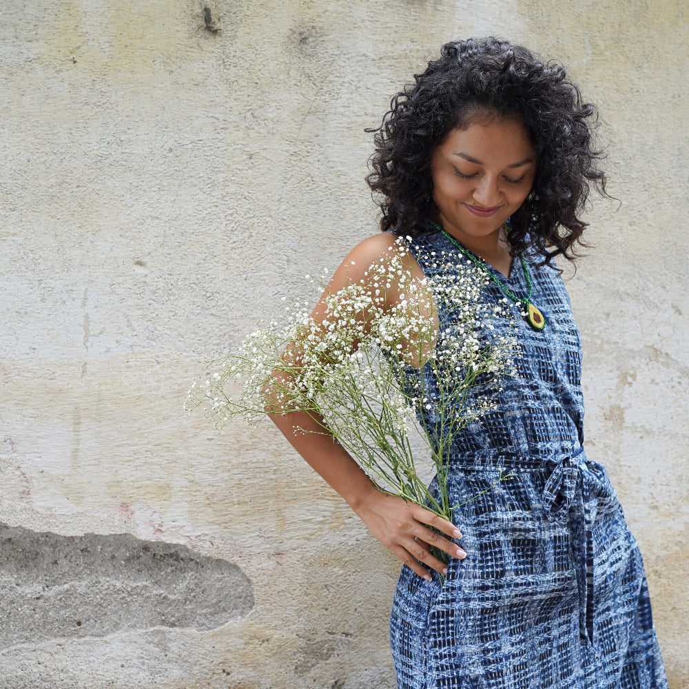 A woman holding a bouquet, she is wearing a blue and white dress ikat fabric.
