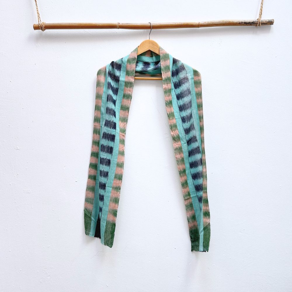Striped and ikat patterned scarf on a hanger against a white background