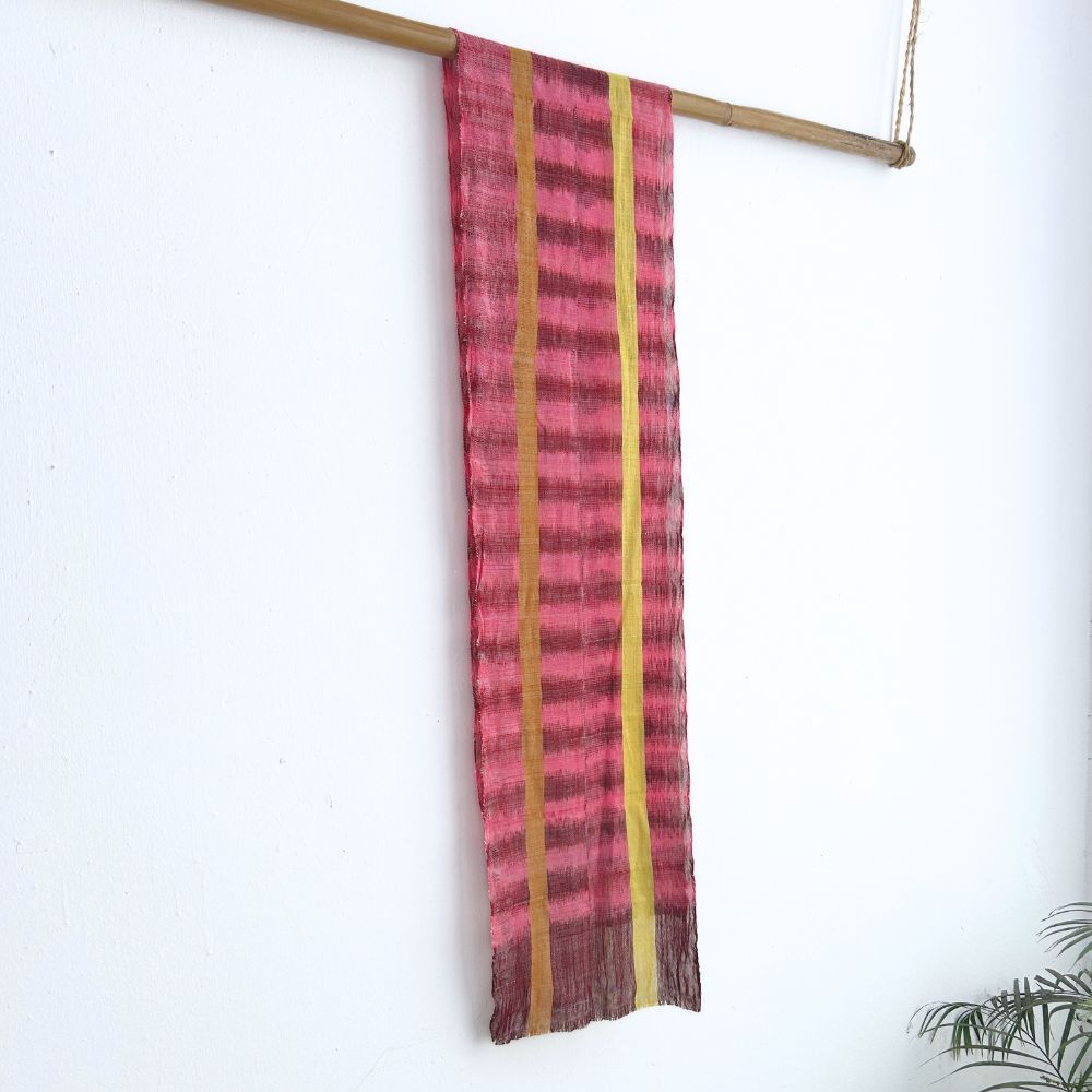 Striped fabric with pink and yellow pattern hanging on a wooden rod against a white background