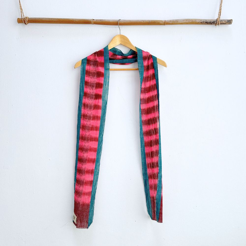 Naturally-dyed vibrant handwoven cotton scarf is placed on a hangar to show its ikat designs