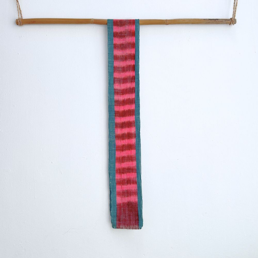 Naturally-dyed vibrant handwoven cotton scarf hangs on a bamboo rod