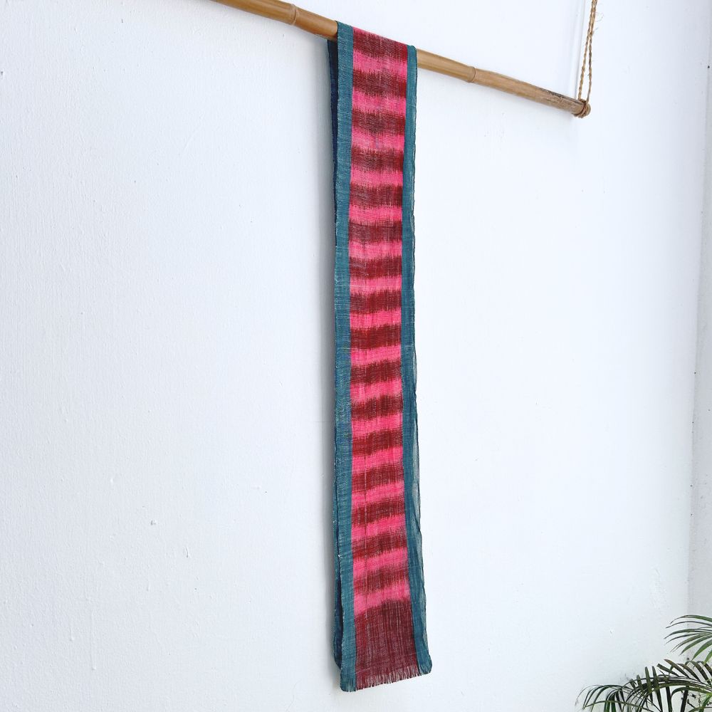 Naturally-dyed vibrant handwoven cotton scarf hangs on a bamboo rod