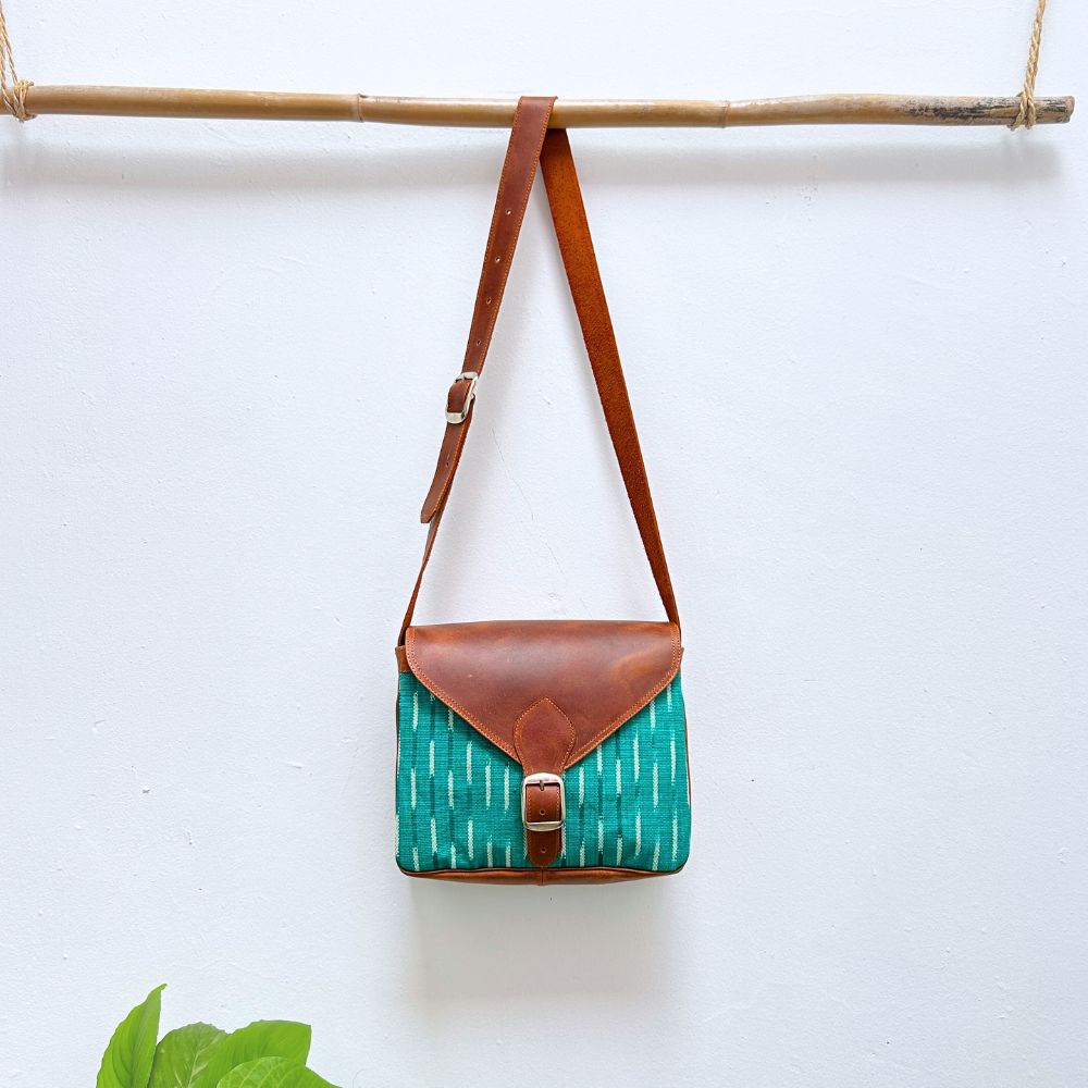 Green patterned bag with brown leather strap on a white background