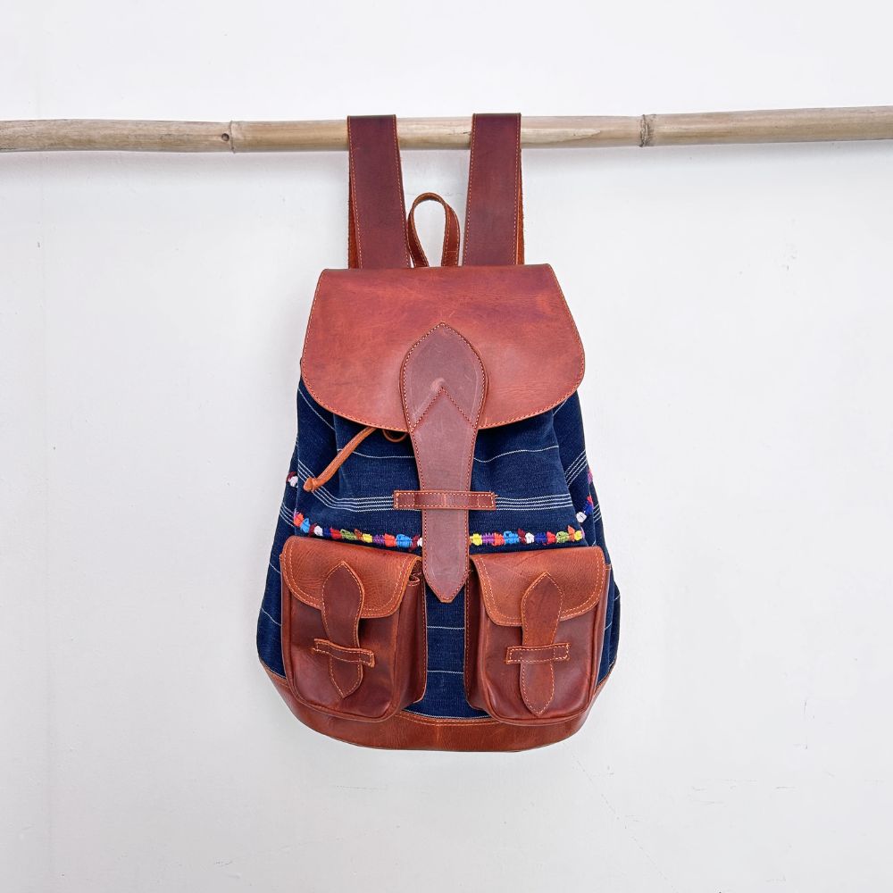 Backpack with brown leather straps and blue corte with colorful randa body on a white background