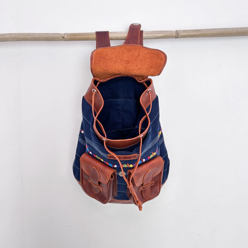 Corte denim backpack with brown leather straps and pockets on a white background