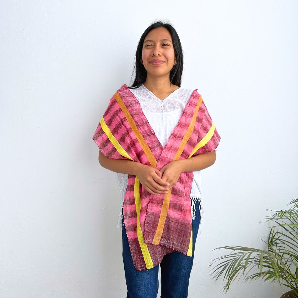 Woman wearing a pink and yellow patterned shawl against a white background
