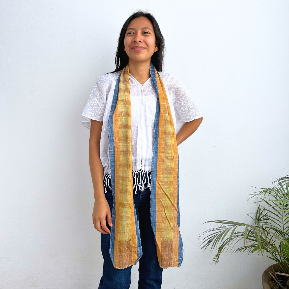 Woman wearing a long yellow and blue scarf against a white background