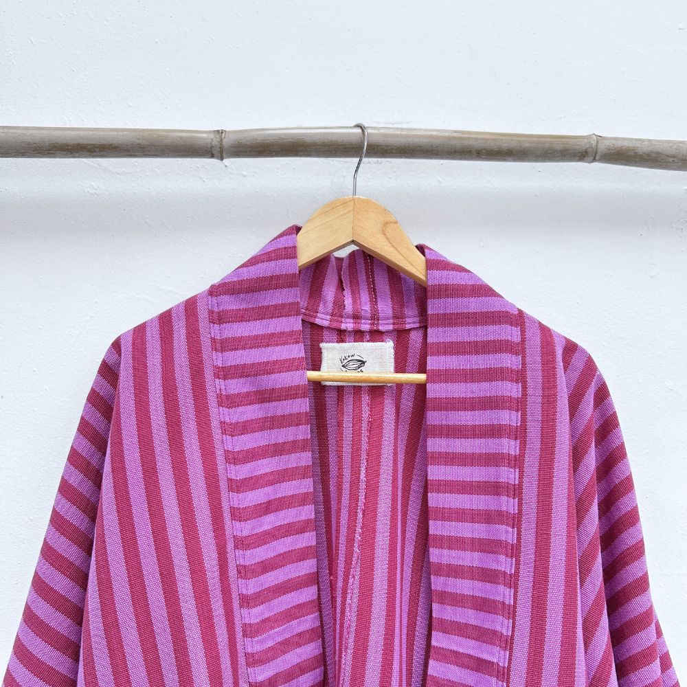 Pink and purple striped garment on a hanger against a white background