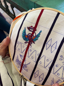 A mythical bird being stitched onto a huipil