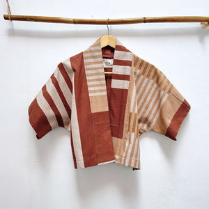 Striped jacket with brown and beige pattern on a hanger against a white background