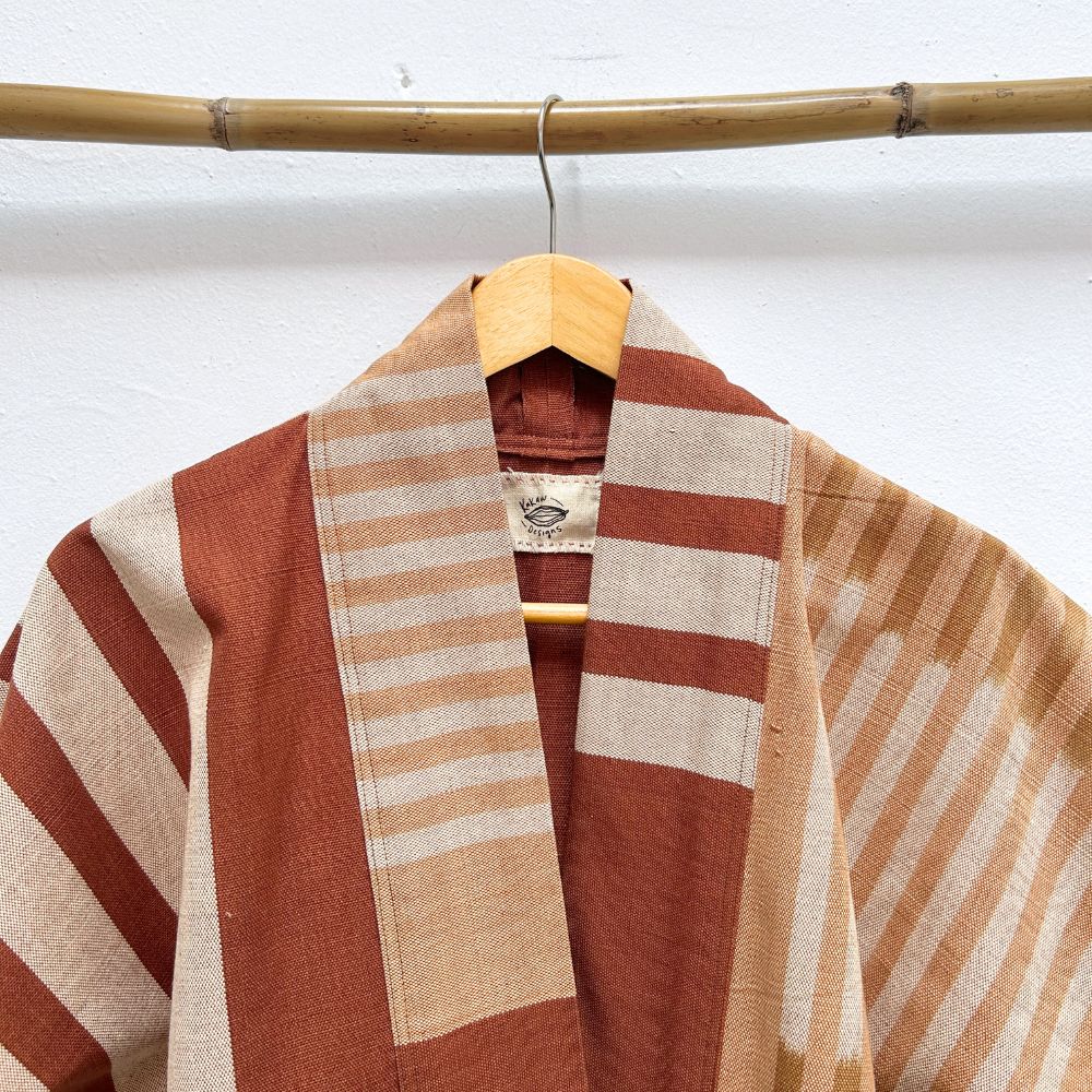 Striped jacket with a wooden hanger against a white wall