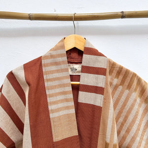 Striped jacket with a wooden hanger against a white wall