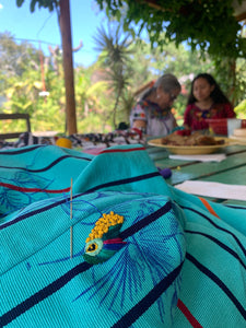 Close-up of a hummingbird being stitched by hand on a güipil base