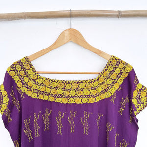 Purple blouse with yellow floral french knot embroidery on a wooden hanger against a white background