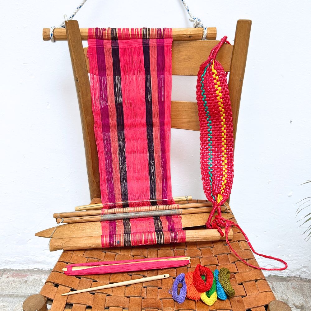 Wooden chair with a loom in pink and colorful yarn on a white background