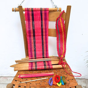 Wooden chair with a loom in pink and colorful yarn on a white background