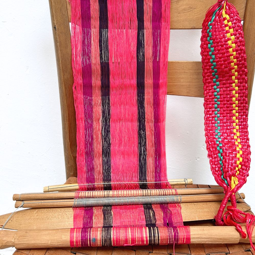 Wooden chair with a loom in pink and colorful yarn on a white background