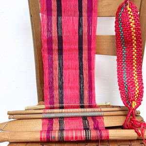 Wooden chair with a loom in pink and colorful yarn on a white background