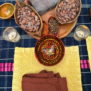 A mise en place of ingredients and tools prepared for the cacao workshop, featuring single-origin cacao beans, allspice, Cobánero chili, and traditional jícaras used throughout the experience.