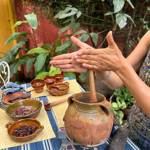 A participant mixing cacao into hot water to fully incorporate the ingredients and create the traditional frothy texture before serving.