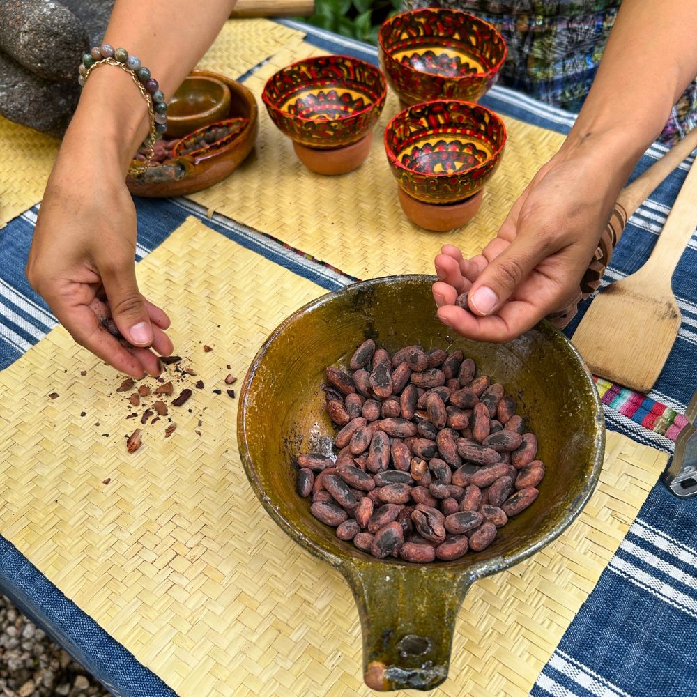 Close up of freshly roasted cacao beans being hand peeled by a participant during the cacao experience.