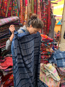 A woman looks at an ikat-filled traditional corte at the Chichicastenango market