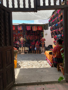 An open handcarved wooden door shows a glimpse of the colorful textiles available at the Chichicastenango market