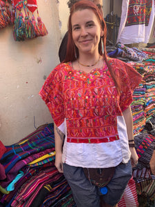 A woman wears a beautiful red and white huipil from San Juan Cotzal found at the Chichicastenango market