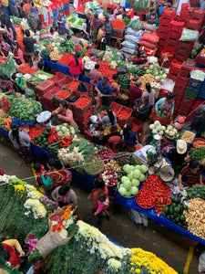A bustling open-air market with various stalls selling fresh produce and traditional textiles, located in Chichicastenango, Guatemala.