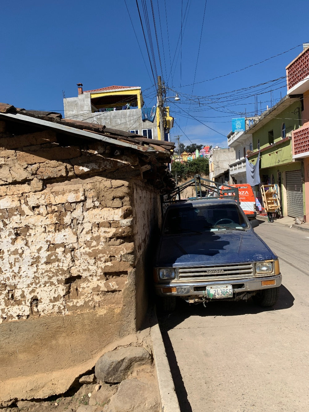 A truck is parked impressively close to a traditional adobe home at Chichicastenango