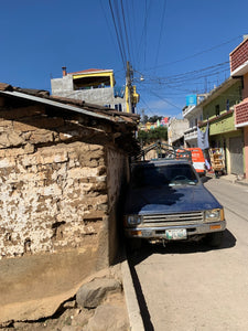 A truck is parked impressively close to a traditional adobe home at Chichicastenango