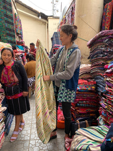 A woman goes through stacks of beautiful traditional textiles at Chichicastenango