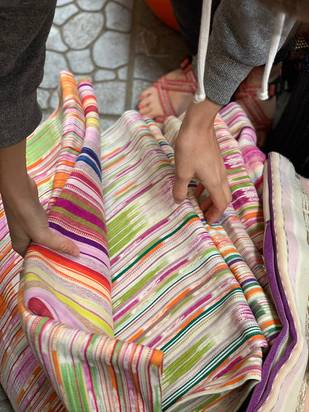 Hands go through pastel-colored vintage textiles at the Chichicastenango market