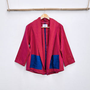 Red and blue jacket on a hanger against a white wall