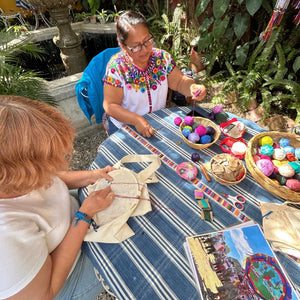 A teacher preparing colorful embroidery threads to demonstrate the next stitching techniques while the student embroiders her own tote bag.