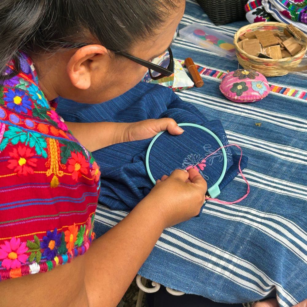 Our teacher Claribel demonstrating the type of stitch used to embroider the flower design drawn on the top.