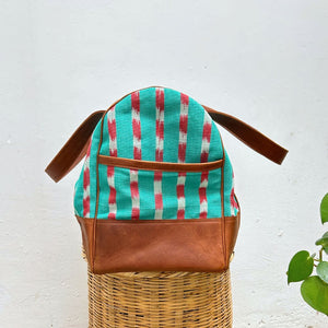 Duffel bag in green and red striped pattern with brown leather on a white background