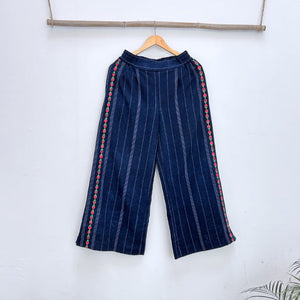 Navy blue pinstripe trousers with strawberries randa embroidery  on a hanger against a white background