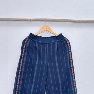 Navy blue pinstripe trousers with strawberries randa embroidery  on a hanger against a white background