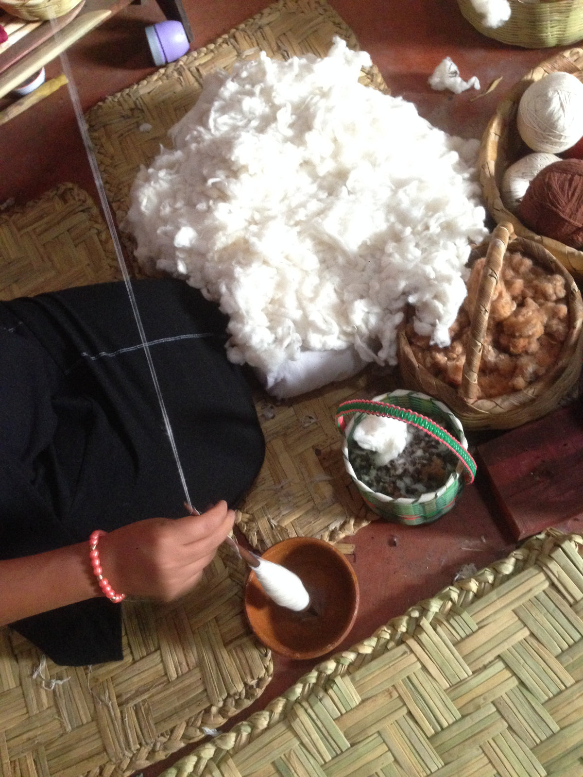 Person working with cotton and yarn on a woven mat