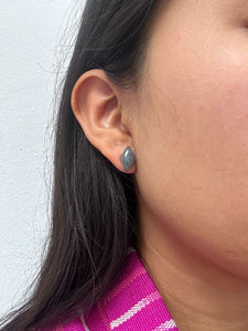 Close-up of an ear wearing a small diamond-shaped medium green jade stud earrings