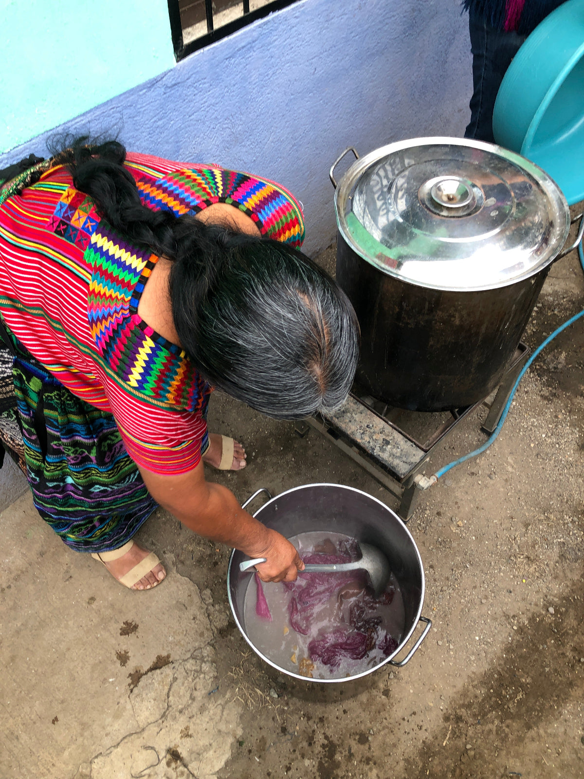 Woman in traditional clothing cooking over a portable stove outdoors