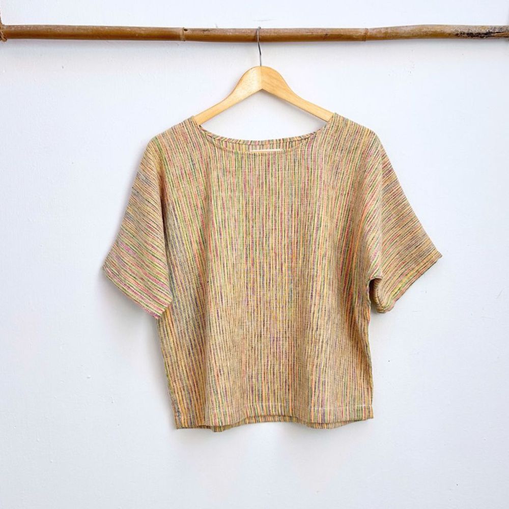 Multicolored top on a wooden hanger against a white wall