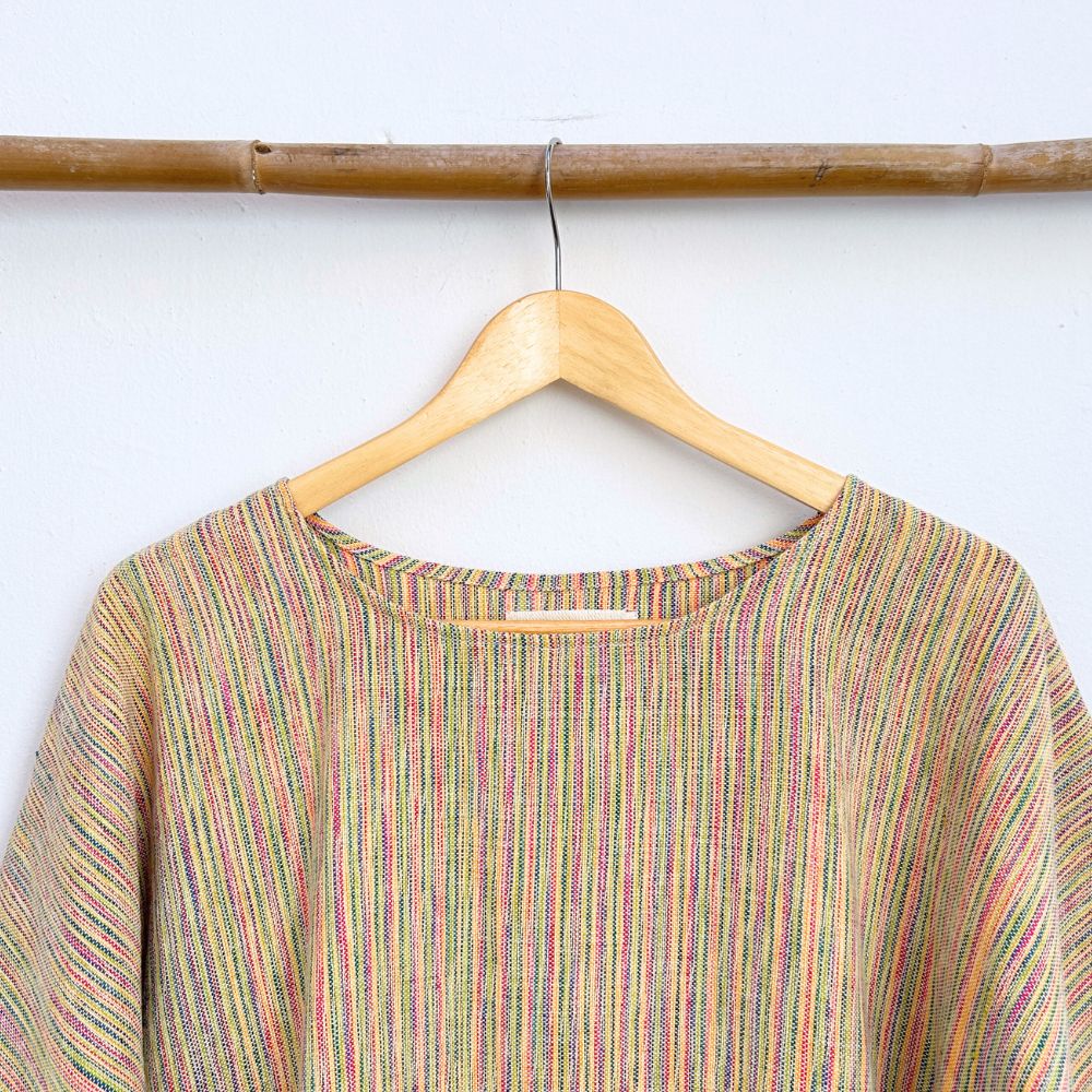 Multicolored striped shirt on a wooden hanger against a white background